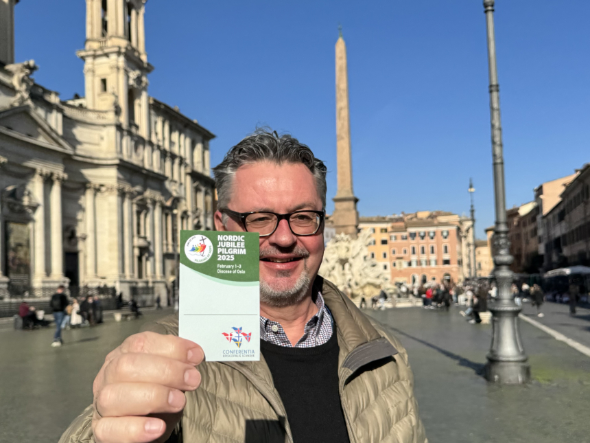 Hans Rossiné holder opp et nordisk pilegrimskort mens han står på Piazza Navona i Roma